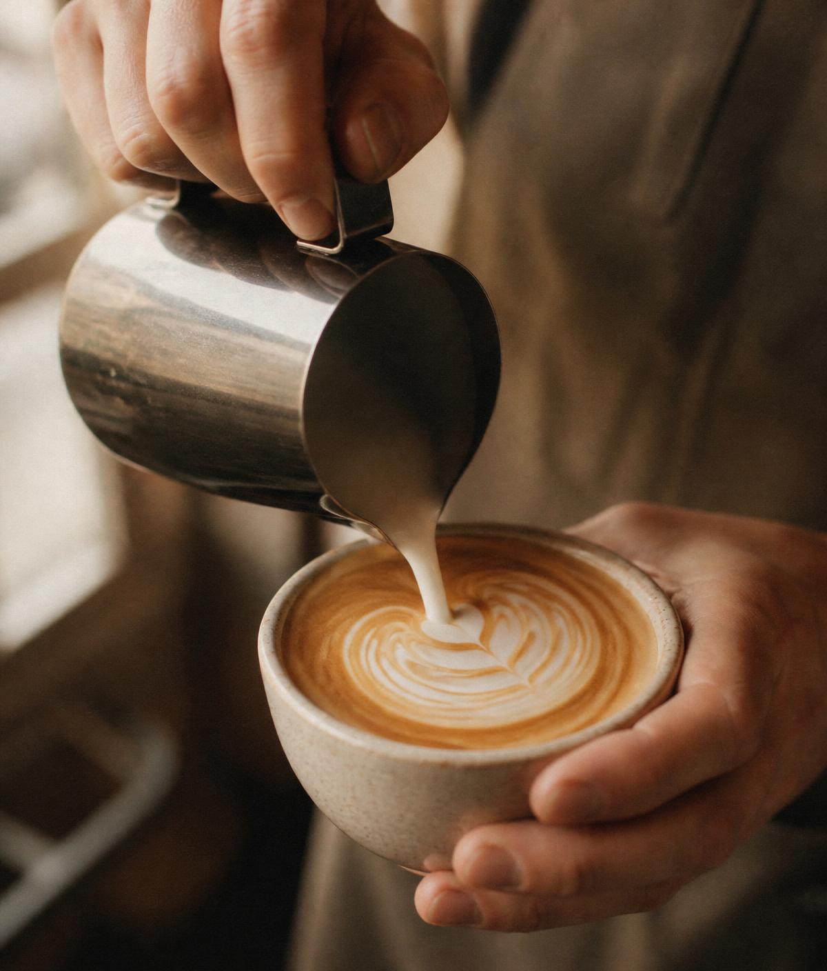 Barista pouring latte art into a ceramic cup